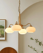 An archway and a framed landscape photo sit behind this Clérachic chandelier's four cream shades.