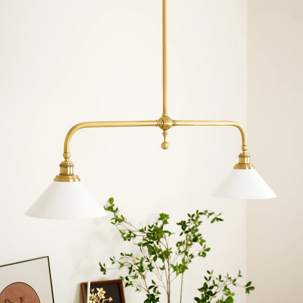 A framed print and trailing plant style the console table below this Clérachic pendant, glowing warm against the wall.