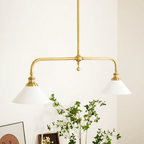 A framed print and trailing plant style the console table below this Clérachic pendant, glowing warm against the wall.