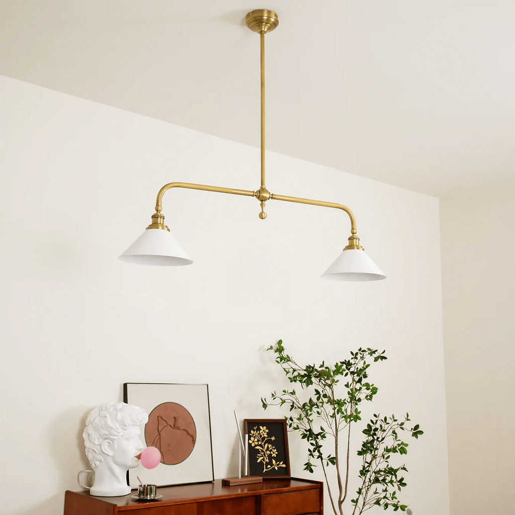 Angled against a cream wall, this Clérachic pendant glows warm above a console table with art and greenery.