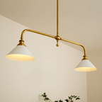 A closer angle on this Clérachic pendant shows both white conical shades glowing warm against a plain cream wall.