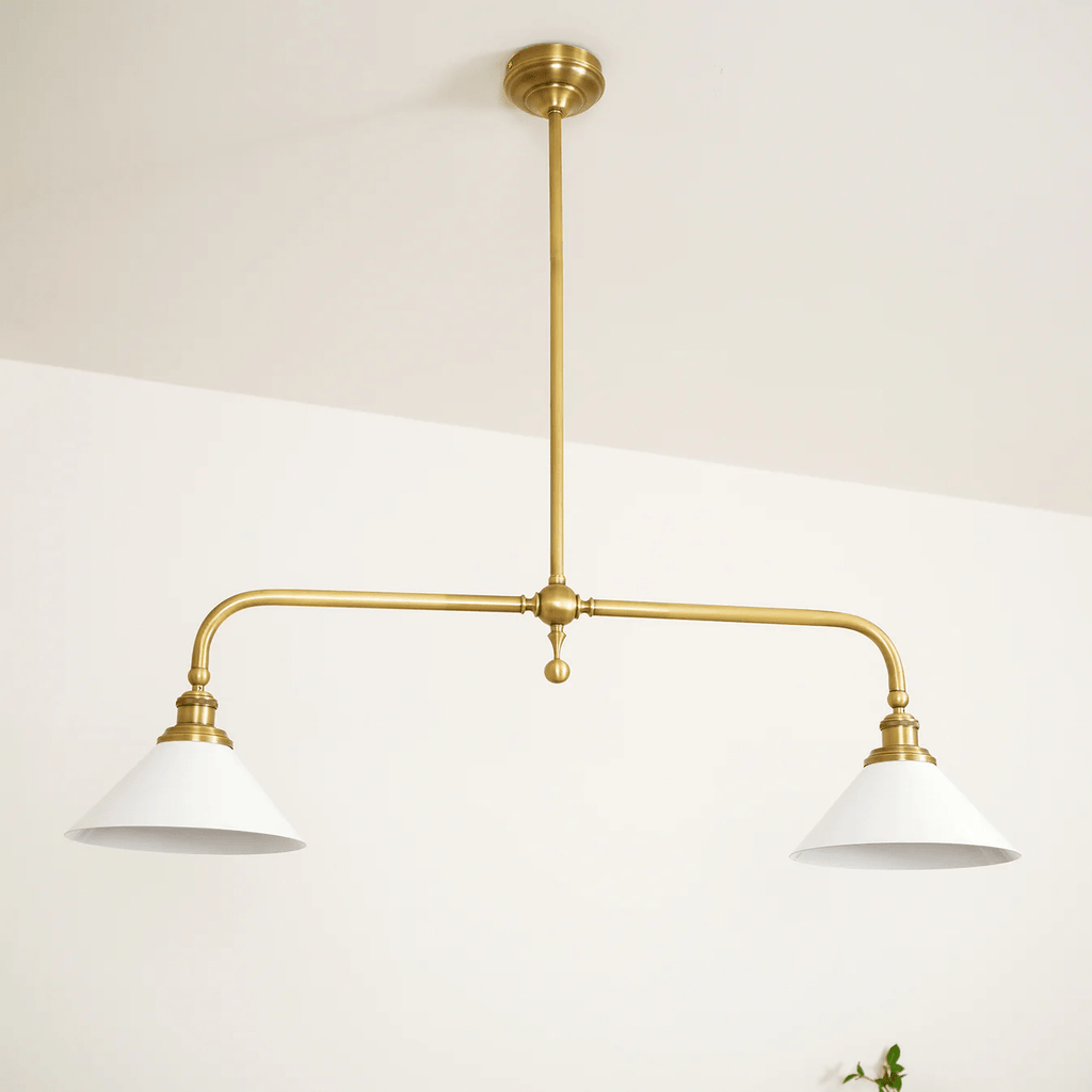 On a plain cream background, this Clérachic pendant stands unlit, a single green sprig at its base.