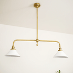 On a plain cream background, this Clérachic pendant stands unlit, a single green sprig at its base.