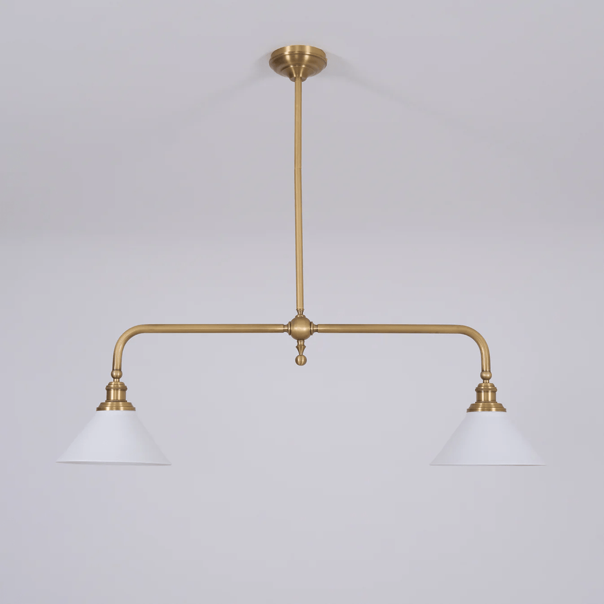 Set on grey, this Clérachic pendant's brass arms and white conical shades sit unlit, seen from a slight angle.