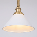 Close view of one shade on this Clérachic pendant, glowing warm beneath its brass elbow arm.