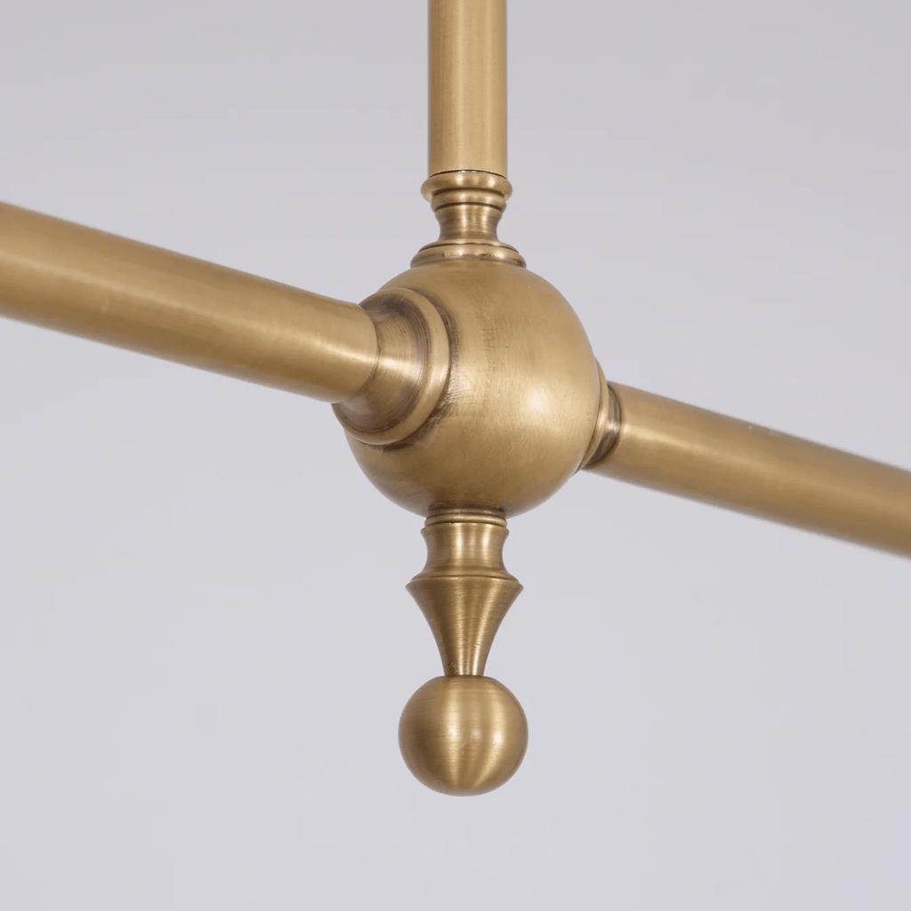 Close view of the central brass hub where this Clérachic pendant's arms and ceiling rod meet.