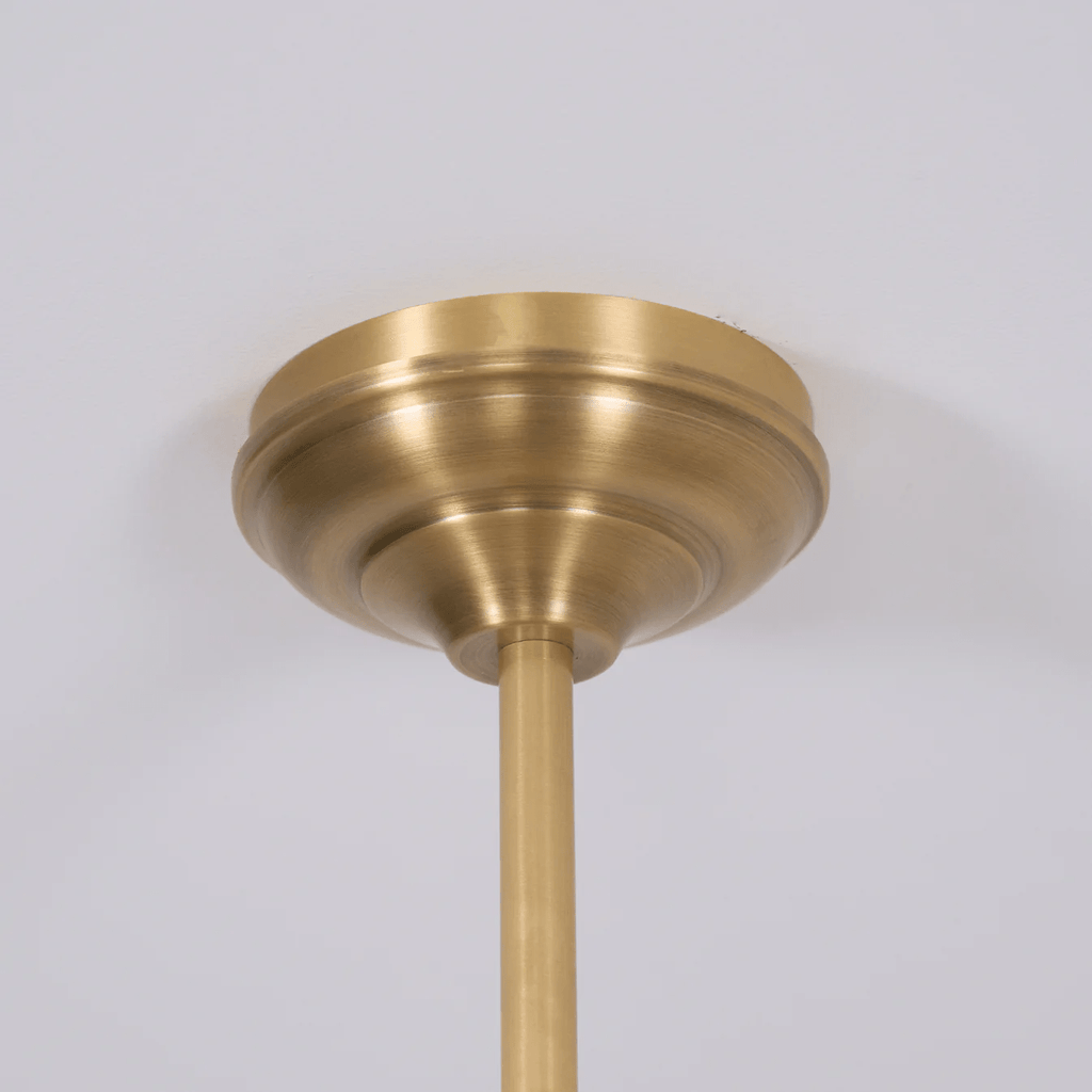 Close view of the round brass ceiling canopy where this Clérachic pendant's rod meets the ceiling.