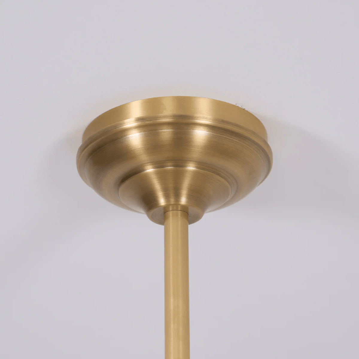 Close view of the round brass ceiling canopy where this Clérachic pendant's rod meets the ceiling.