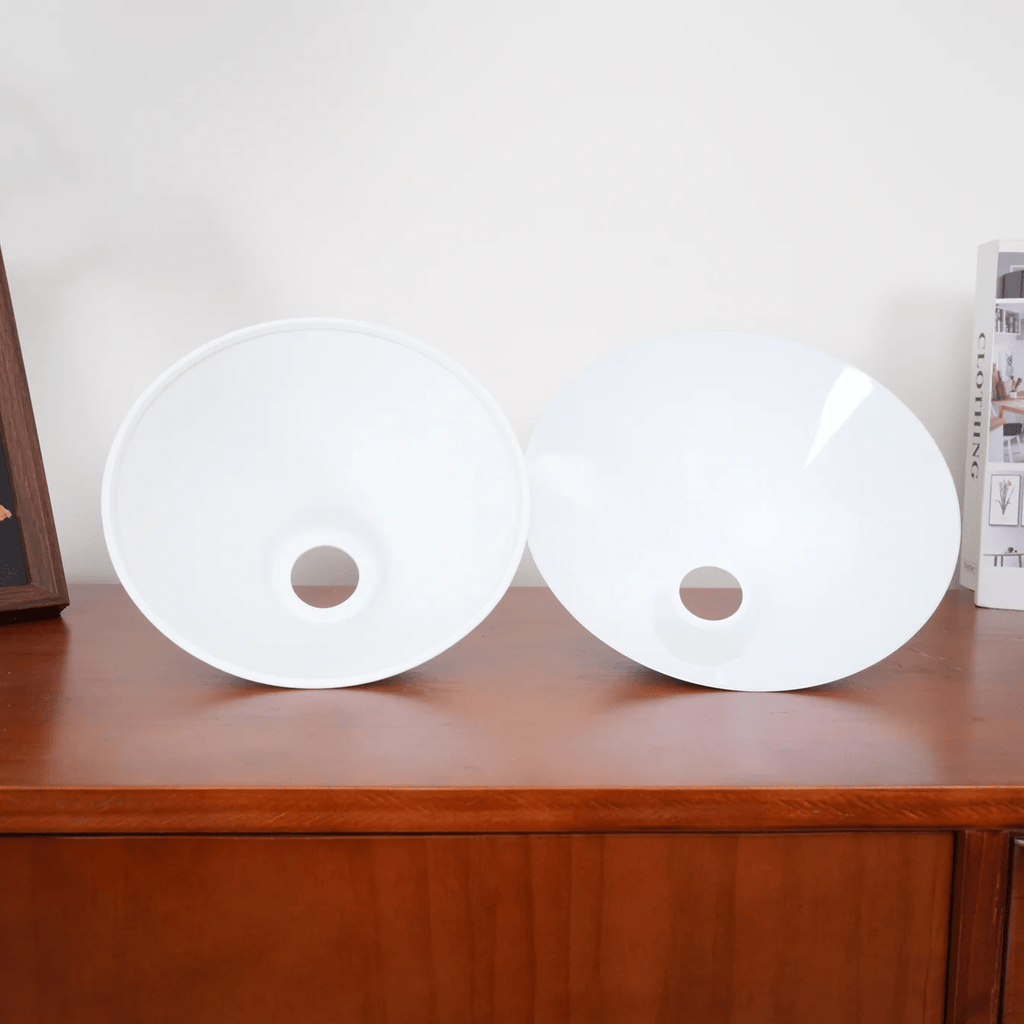 Two white conical shades from this Clérachic pendant rest face-up on a wood dresser, their centre sockets open.