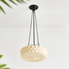 A close angled view of this beige fluted-glass Clérachic pendant, unlit, its fluted ribs and sunburst diffuser visible from below.