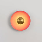 This coral-orange Clérachic wall light's antique copper centre sits small and bright against the warm shade.