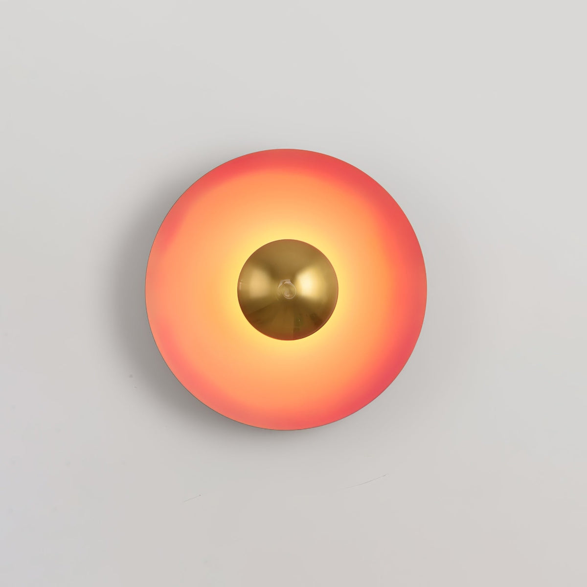 This coral-orange Clérachic wall light's antique copper centre sits small and bright against the warm shade.