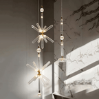 Three Clérachic pendants hang at staggered heights, lit, against a dark stone wall streaked with sunlight.