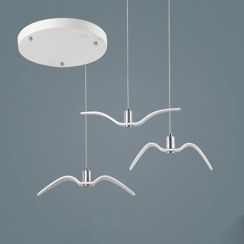 On a slate-blue backdrop, three white bird-shaped pendants from this Clérachic fixture hang from a round white canopy at staggered lengths.