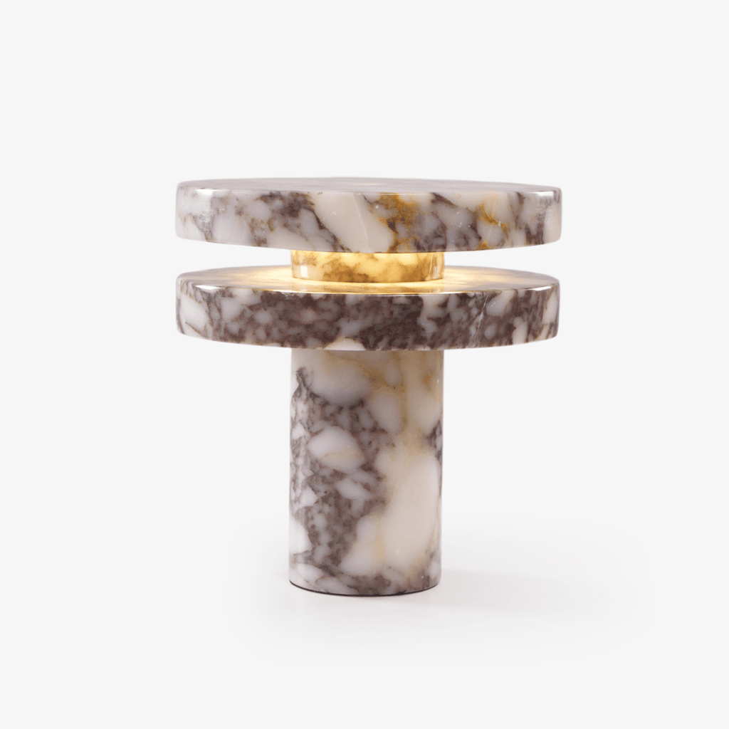 Clérachic table lamp shown alone on a plain background, two marble discs stacked above a marble column base, LED lit.