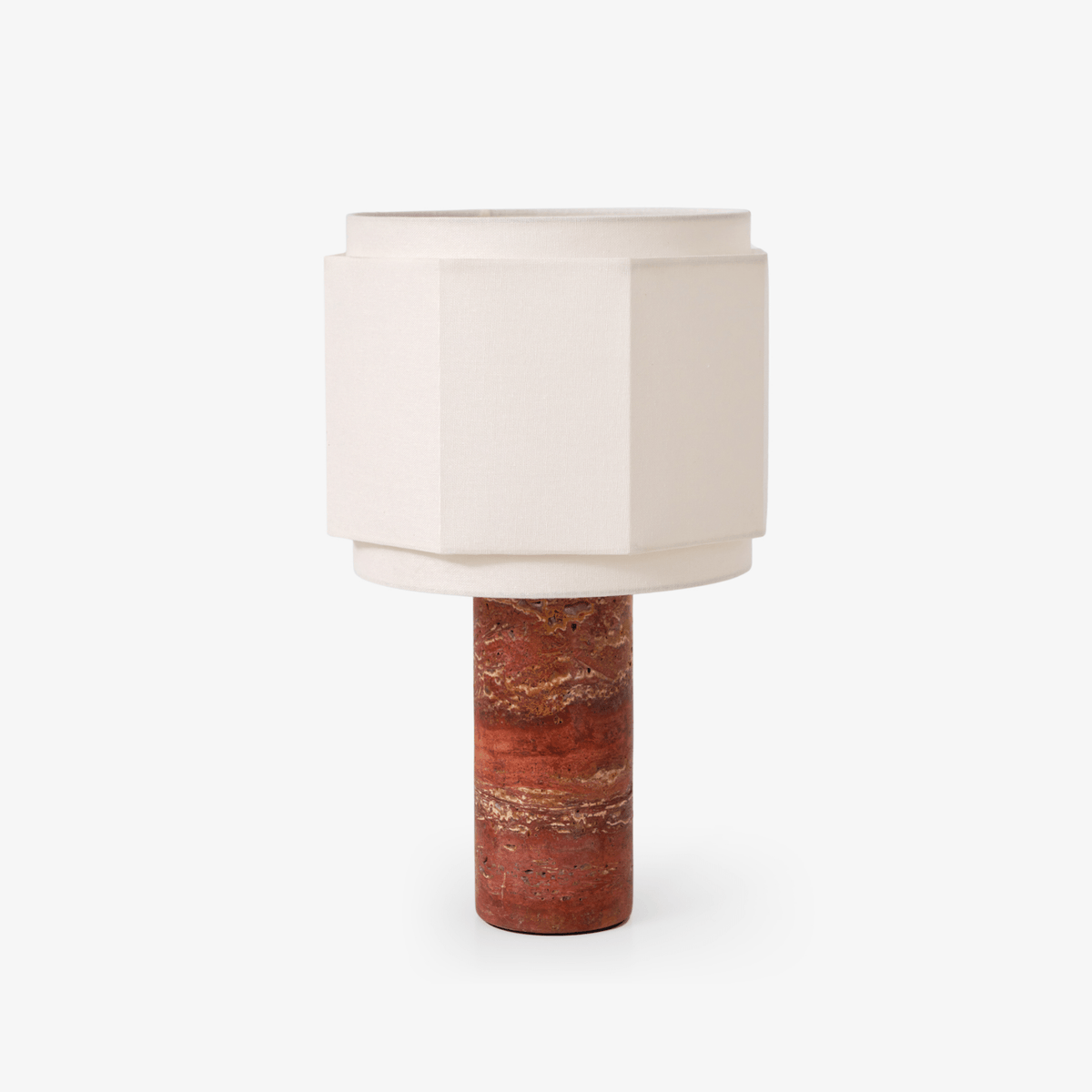 Ivory hexagonal fabric shade on a red travertine base, this Clérachic table lamp shown alone on white.