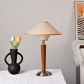 Fabric shade table lamp on a warm walnut wood base glowing softly