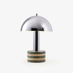 Clérachic table lamp shown alone on a plain background, its mirror-polished chrome dome set above a green and beige marble base.