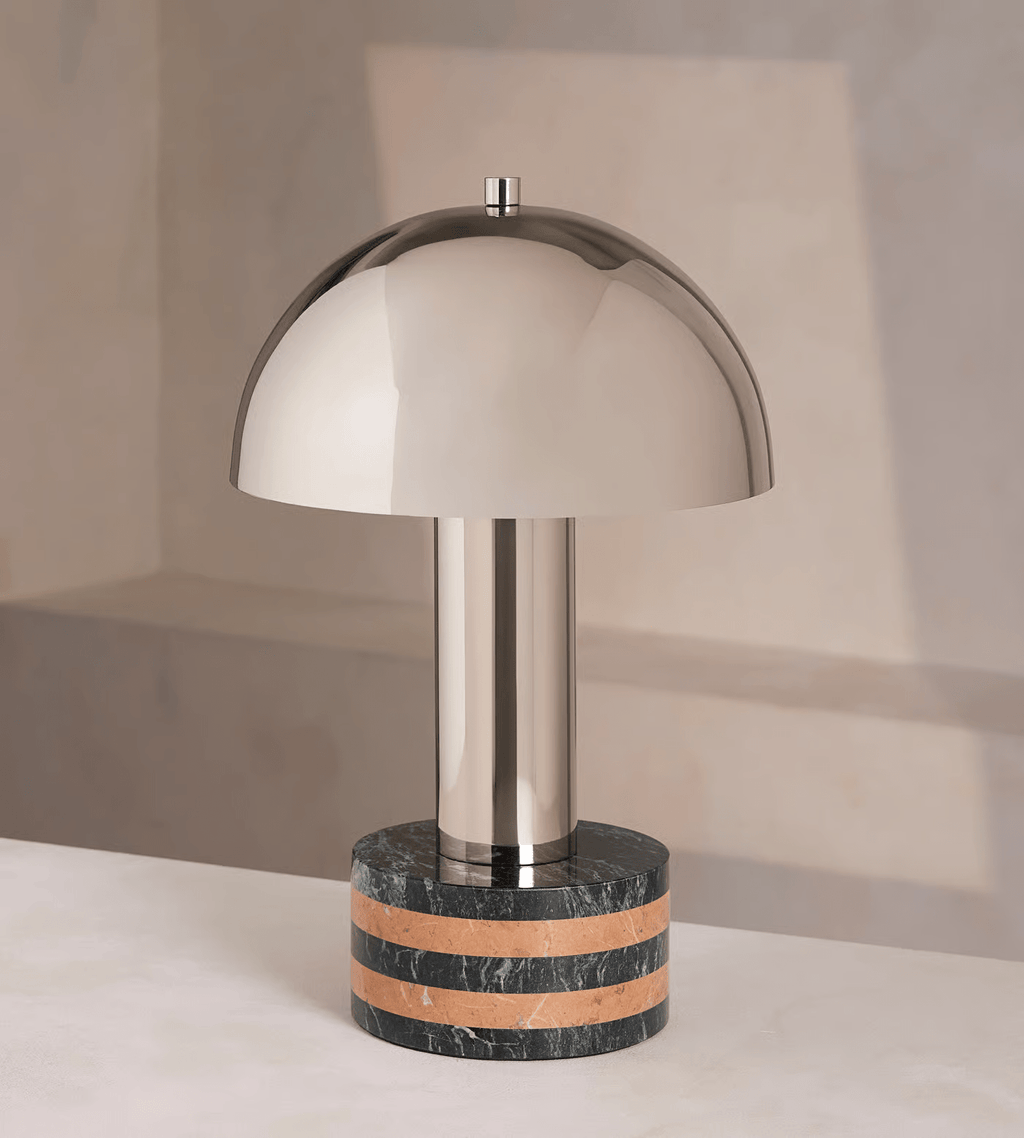 Clérachic lamp variant with a polished metal dome and a dark marble base banded in terracotta, unlit on a plain backdrop.