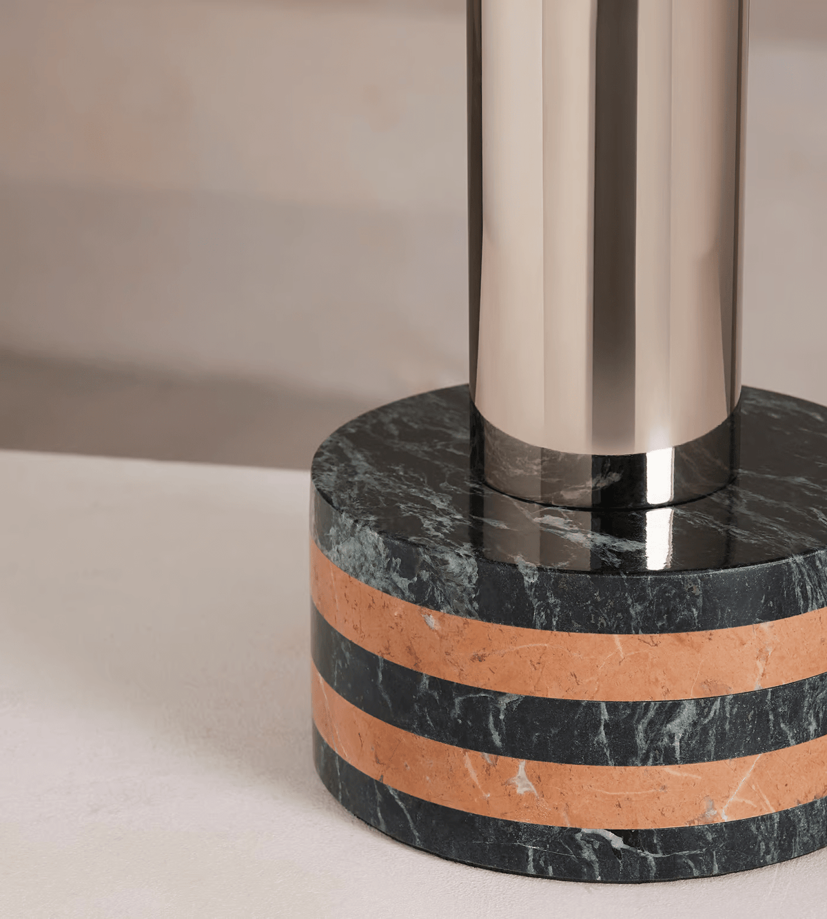 Close-up of the Clérachic lamp's dark marble base, the terracotta stripe banding it just below the polished metal column.