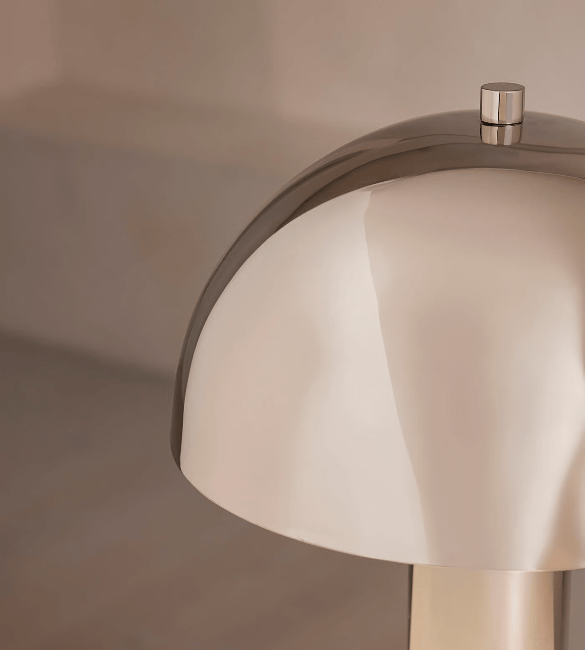 Macro crop of the Clérachic lamp's domed shade edge and finial, the polished metal reflecting the room around it.