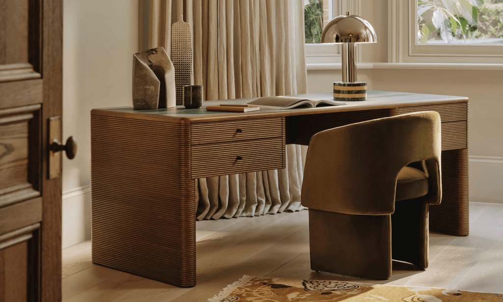 Clérachic table lamp set small in a home office scene, on a wooden desk beside a chair and an open door.