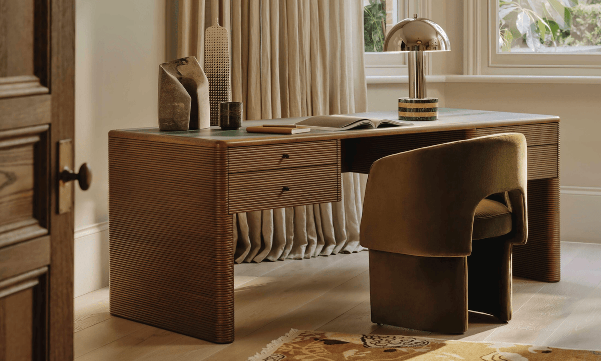Clérachic table lamp set small in a home office scene, on a wooden desk beside a chair and an open door.
