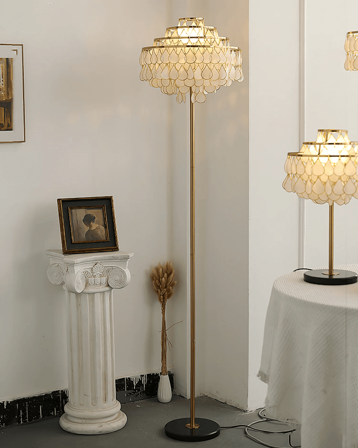 A closer view shows this Clérachic floor lamp's tiered shade beside a plaster column and a framed portrait.