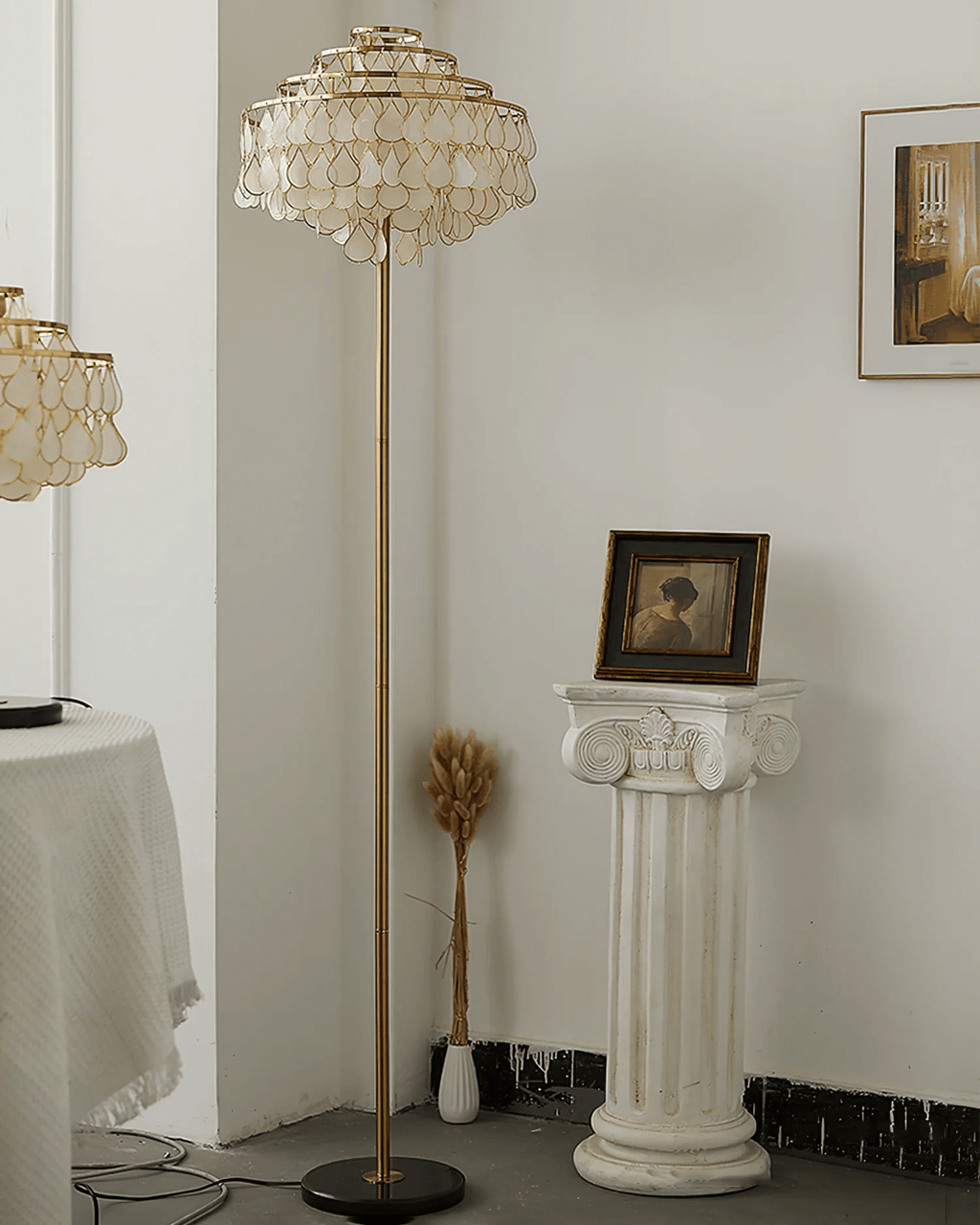 This Clérachic floor lamp rises beside a plaster pedestal topped with dried wheat stems and a small portrait.