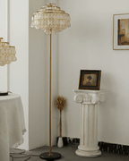 This Clérachic floor lamp rises beside a plaster pedestal topped with dried wheat stems and a small portrait.