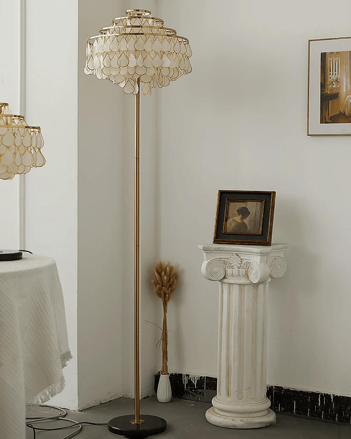 This Clérachic floor lamp rises beside a plaster pedestal topped with dried wheat stems and a small portrait.