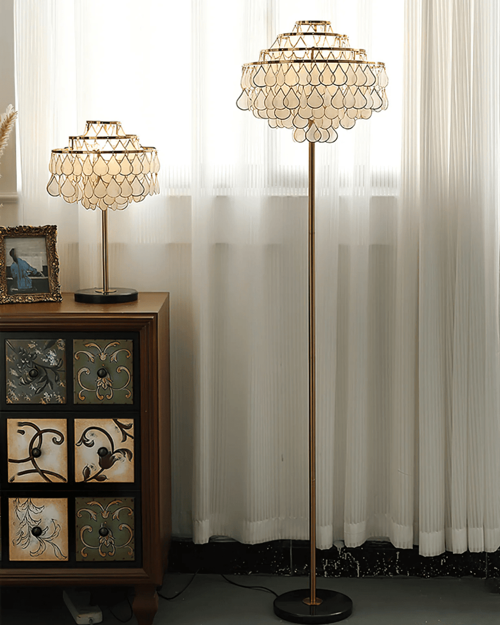 Sheer curtains frame this Clérachic floor lamp as it stands taller than a patterned wood cabinet nearby.