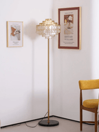 Tucked into a plain corner, this Clérachic floor lamp sits below framed prints beside a mustard chair.