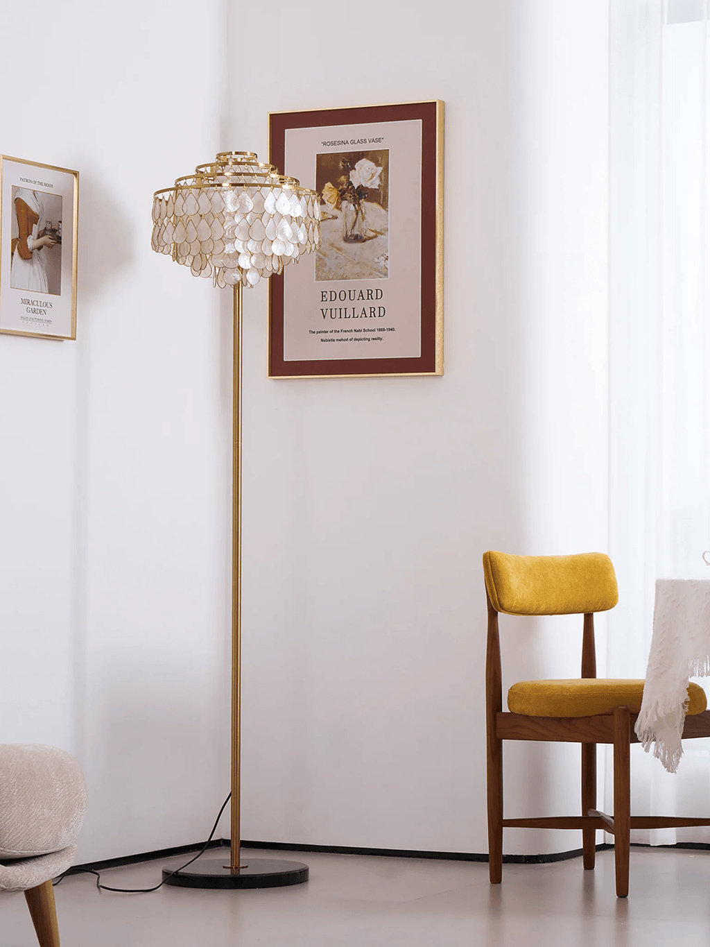This Clérachic floor lamp stands in a bare corner next to a framed art print and a mustard velvet chair.