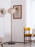 This Clérachic floor lamp stands in a bare corner next to a framed art print and a mustard velvet chair.