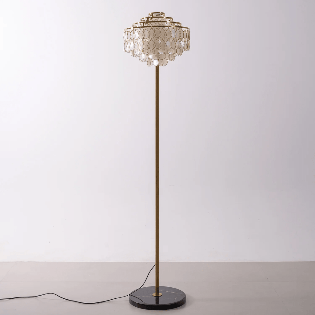 This Clérachic floor lamp stands alone, its shell-petal shade catching light from above on a plain backdrop.