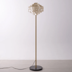 This Clérachic floor lamp stands alone, its shell-petal shade catching light from above on a plain backdrop.