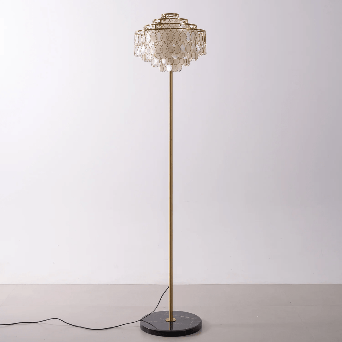 This Clérachic floor lamp stands alone, its shell-petal shade catching light from above on a plain backdrop.