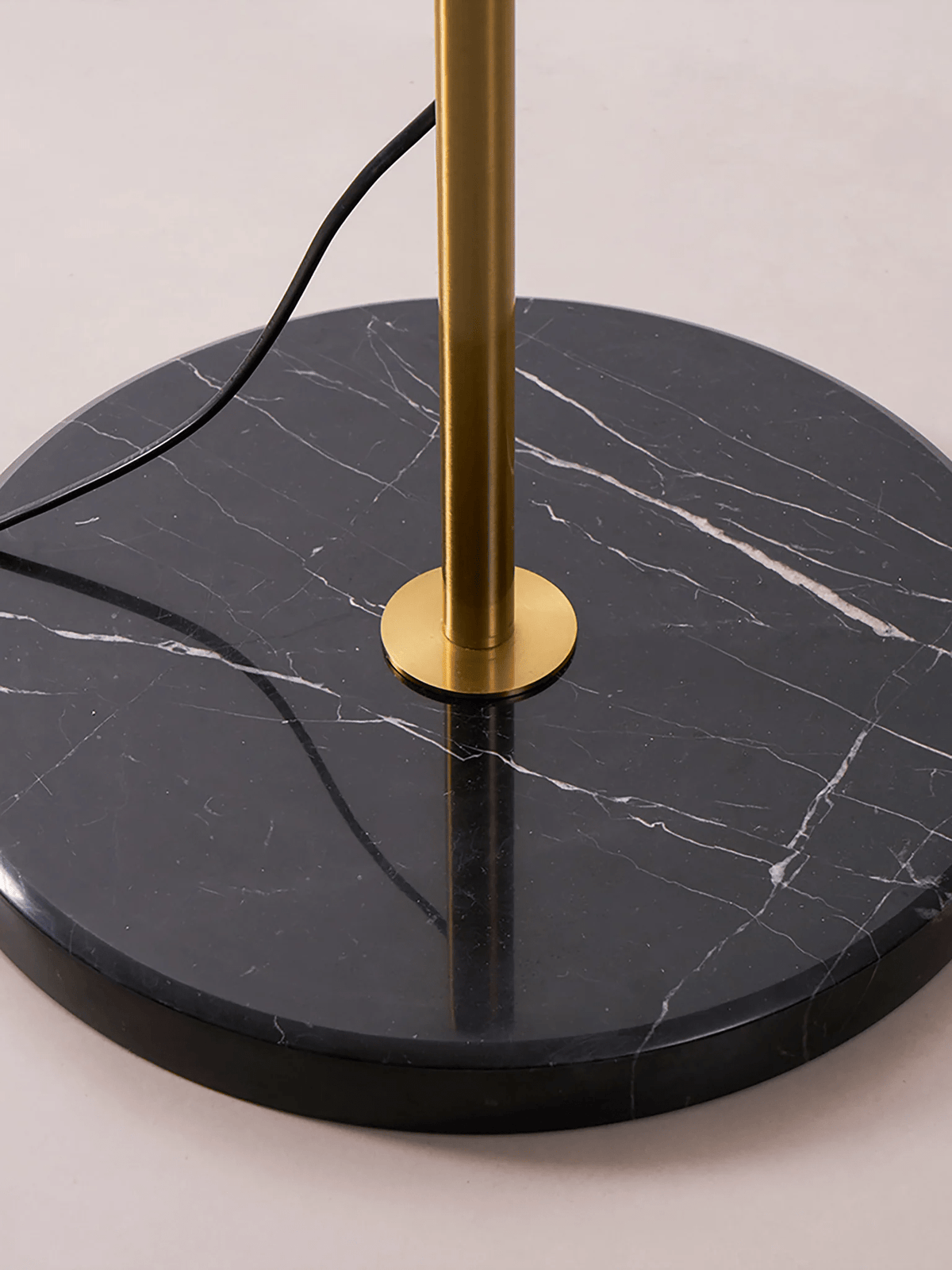 Close view of the black marble base and gold-toned stem of this Clérachic floor lamp.