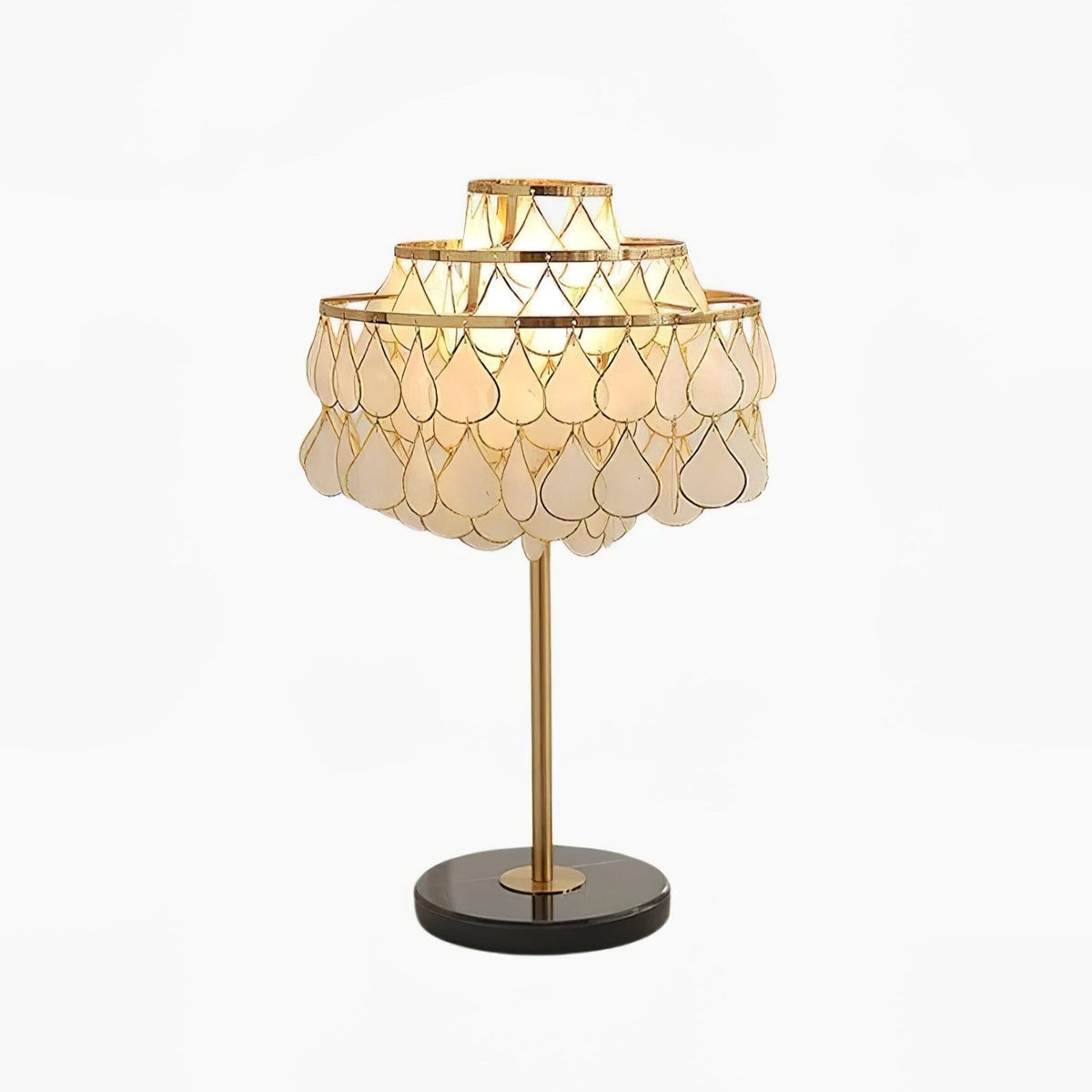Layered teardrop-shaped shell pieces form the glowing dome shade on this Clérachic table lamp, set on a slender gold stem with a dark round base.
