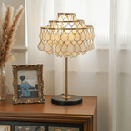 Clérachic table lamp on a dark wood sideboard beside a vintage framed photograph, lit by sheer curtain daylight.