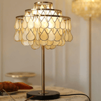 Clérachic table lamp shown full-length and glowing on a round table dressed with croissants and blueberries.
