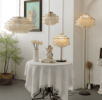 Three Clérachic lamps, a hanging pendant and two floor-height pieces, glowing around a linen-draped round table.
