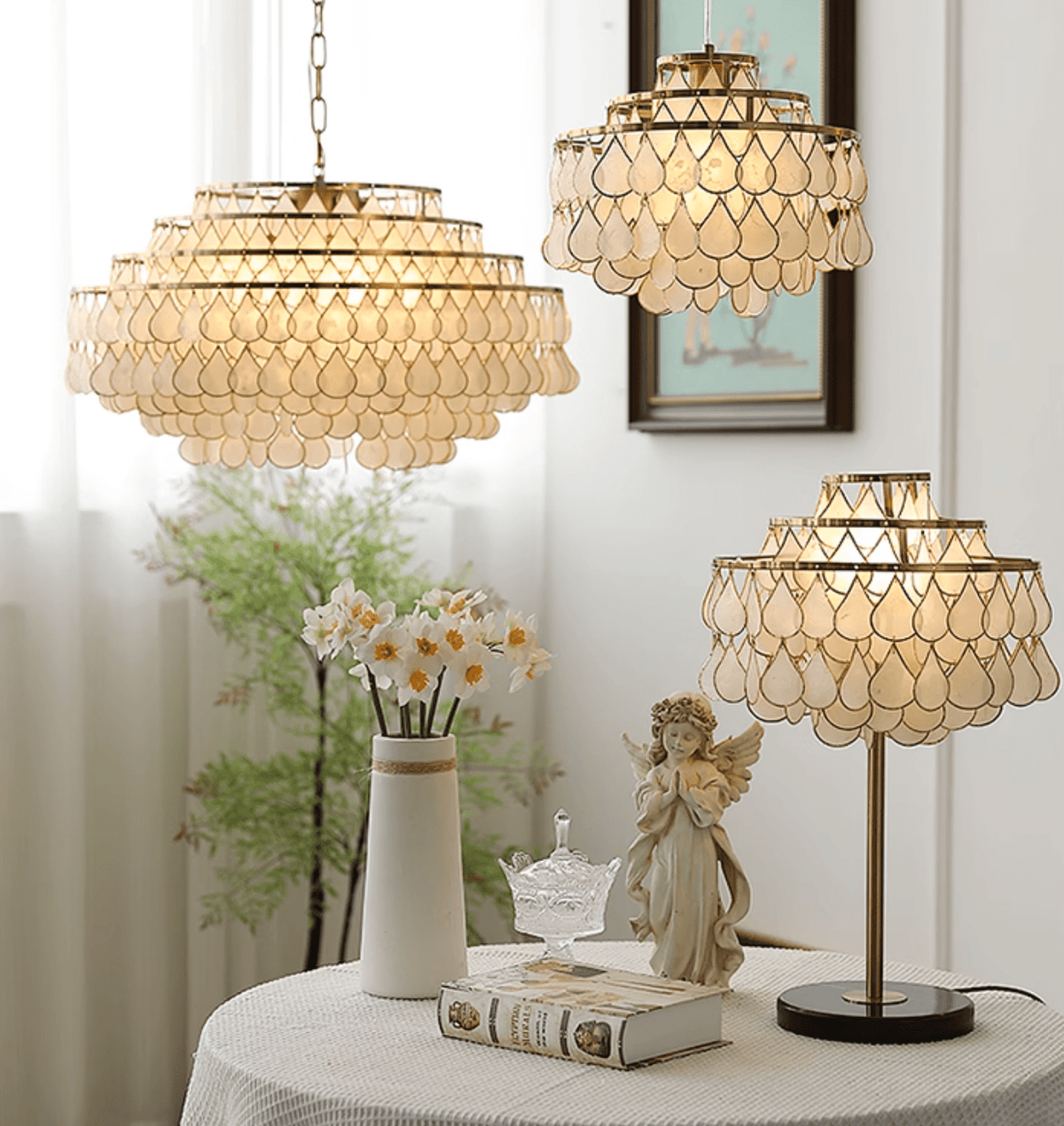 Clérachic table, floor and pendant lamps glowing near a window, with daffodils, an angel figurine and a book.