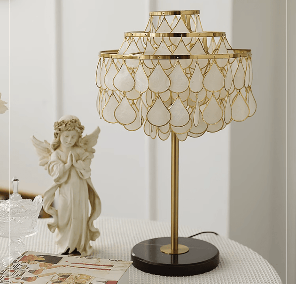 Clérachic table lamp beside a praying angel figurine and a glass trinket dish, with cards spread on the table.