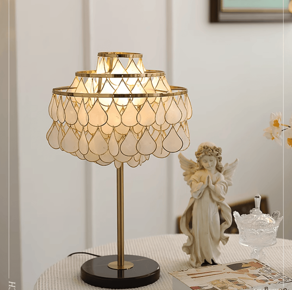 Clérachic table lamp glowing beside a praying angel figurine and playing cards set out on a round table.