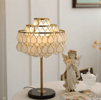 Clérachic table lamp glowing beside a praying angel figurine and playing cards set out on a round table.
