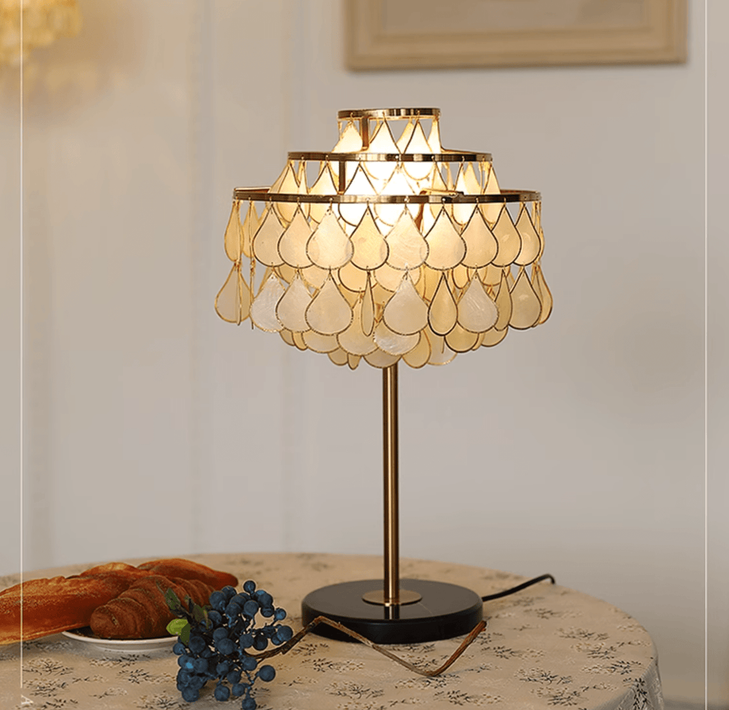 Close-up of the Clérachic table lamp's teardrop shade glowing above a plate of croissants and blueberries.