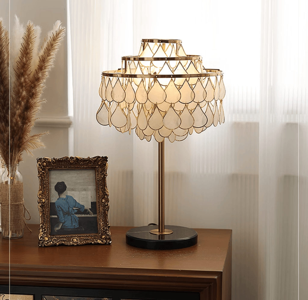 Clérachic table lamp lit on a dark wood sideboard, a vintage framed portrait photograph propped beside it.