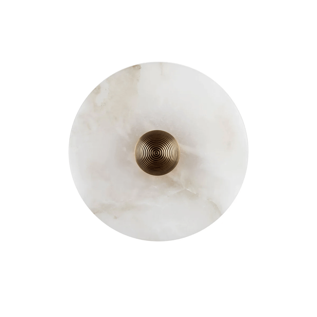 Single alabaster disc sconce, unlit, with warm brass hardware centred on cool white stone.